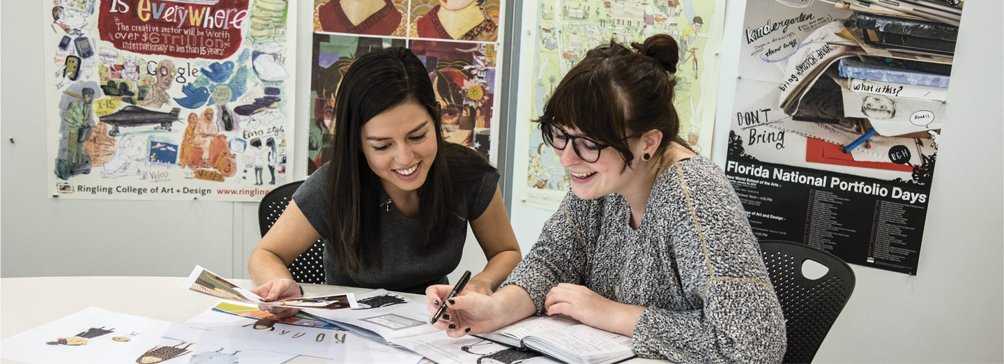 Two smiling students working with books on a table